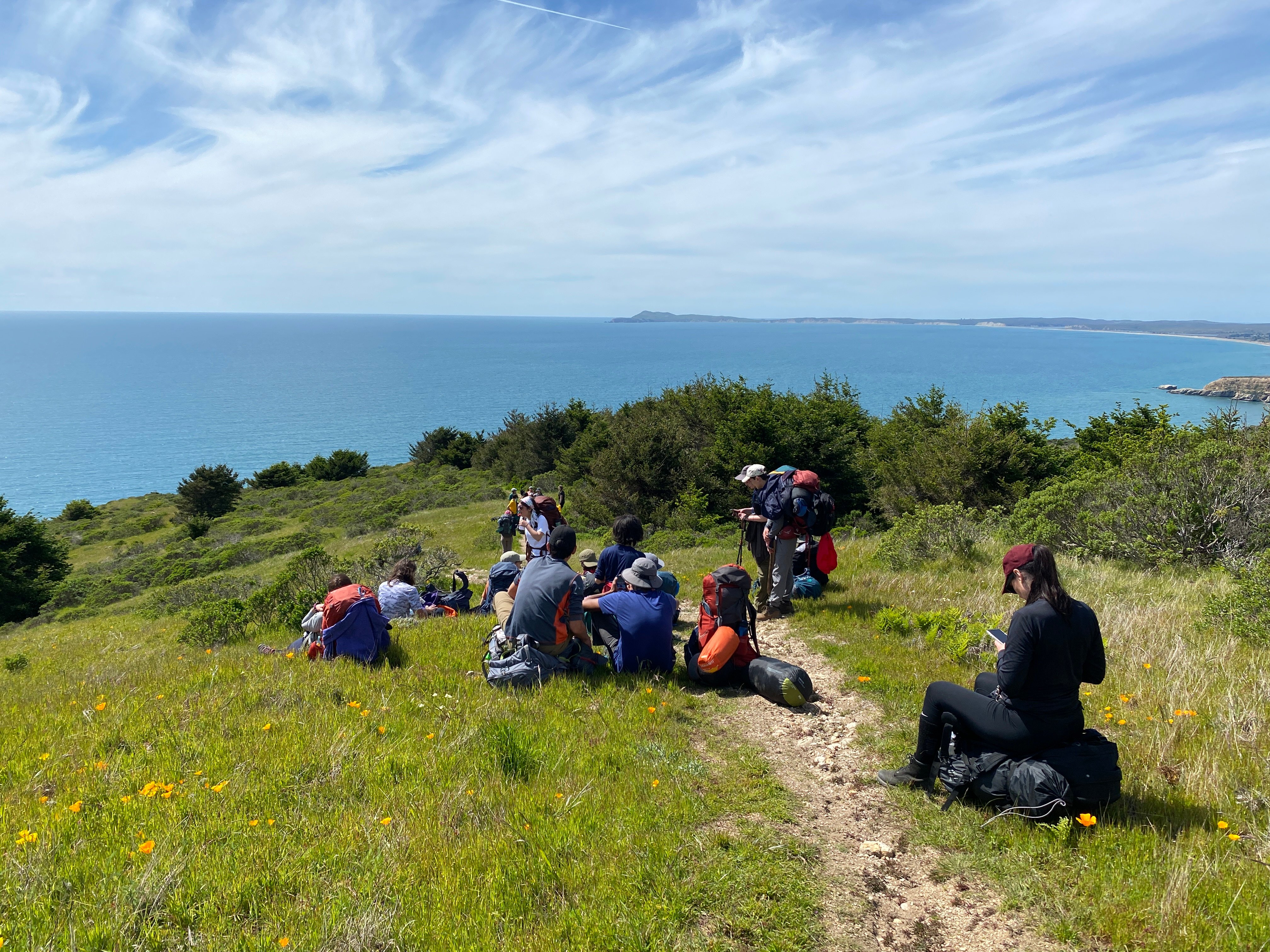 Students resting on their hike on a bluff overlooking the Pacific Ocean.
