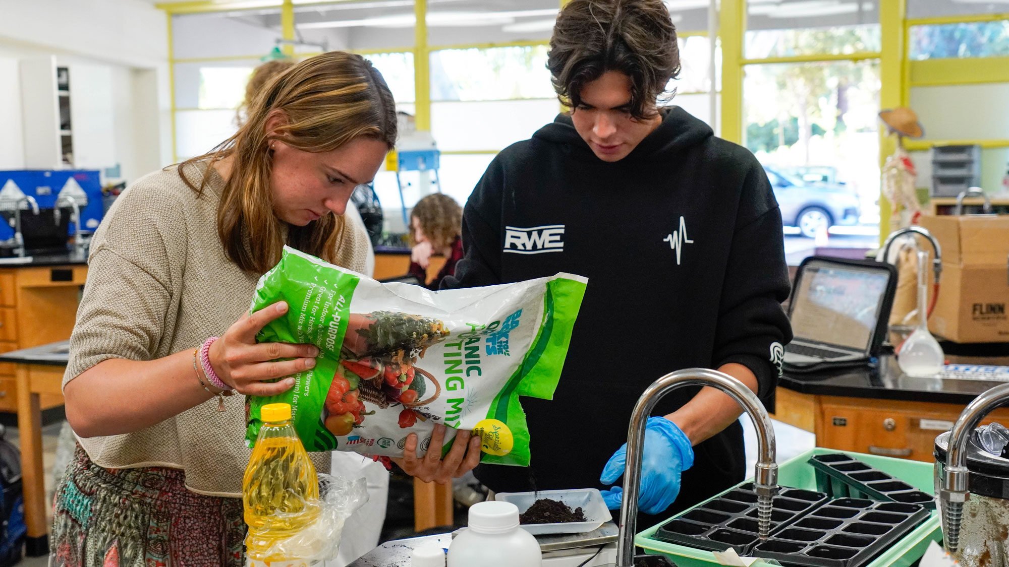 Two students weighing out soil