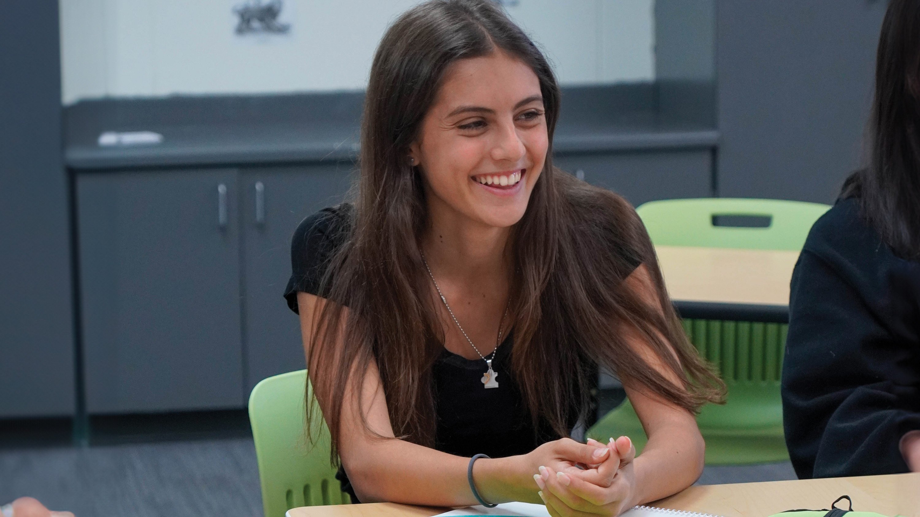 A female student in class smiling during a class discussion.