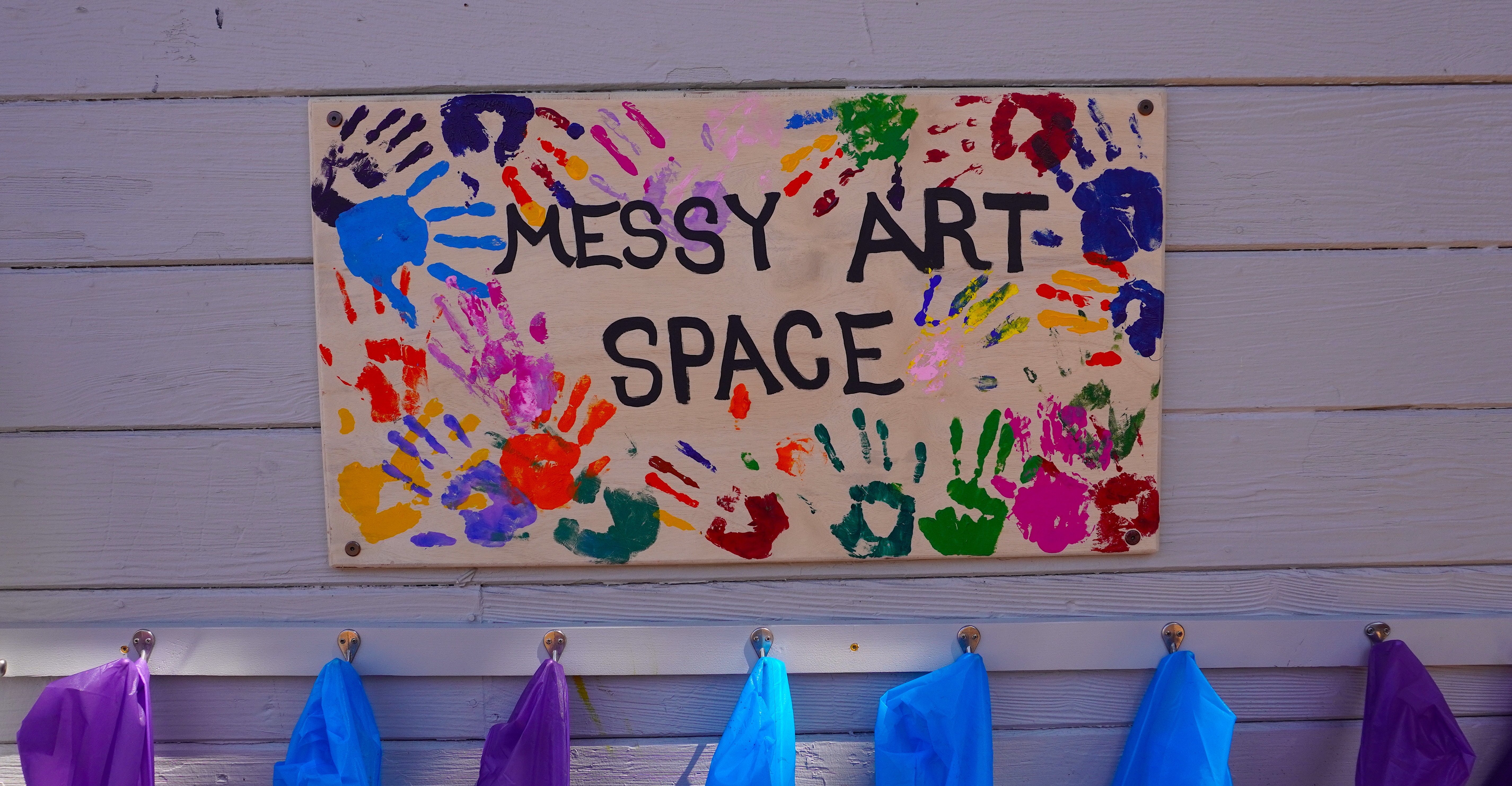 The Messy Art Space entrance sign with a rainbow border of handprints from all the teachers and staff members who made the space possible