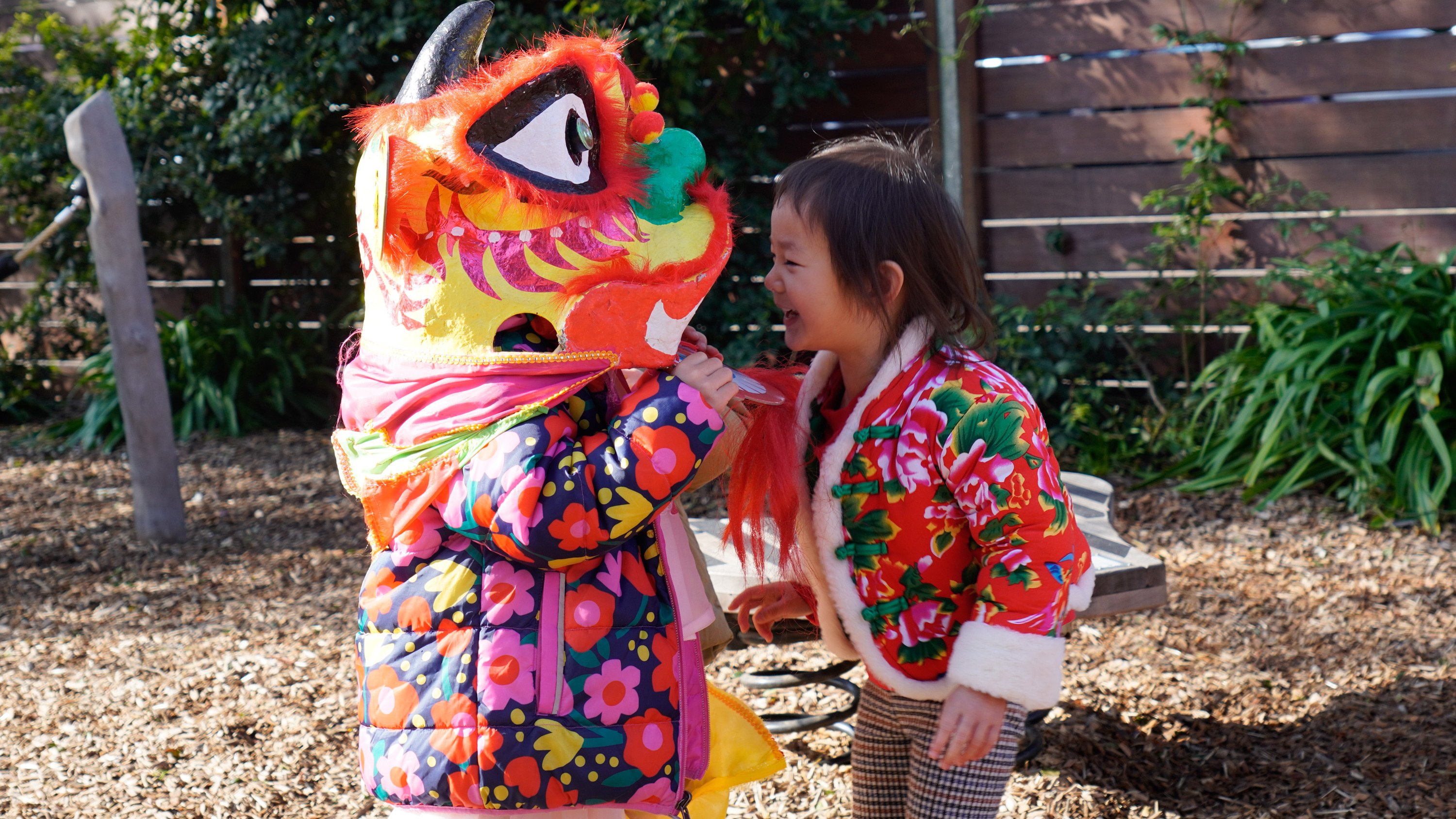 Early Years students playing with dragon masks.