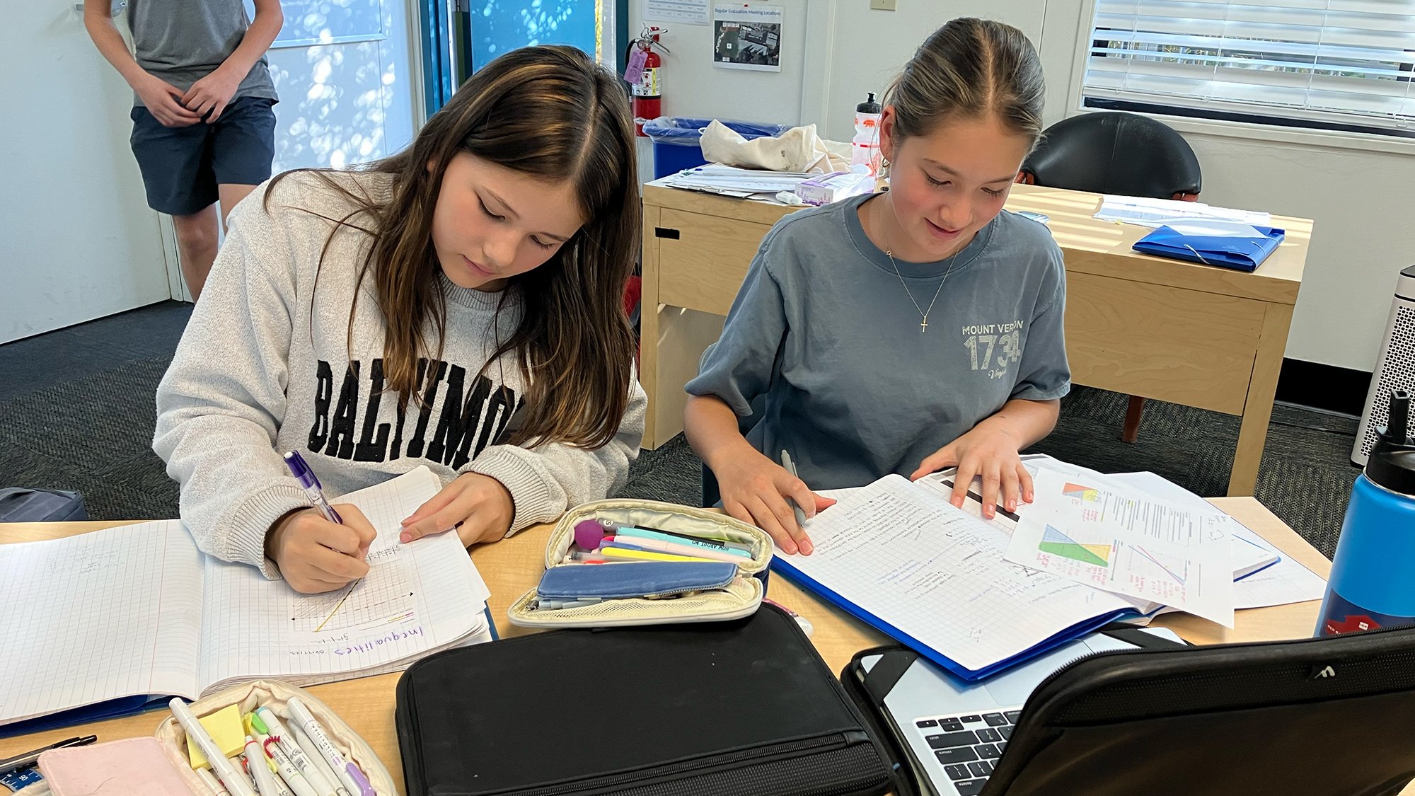 Two middle school female math students working together at their desk.