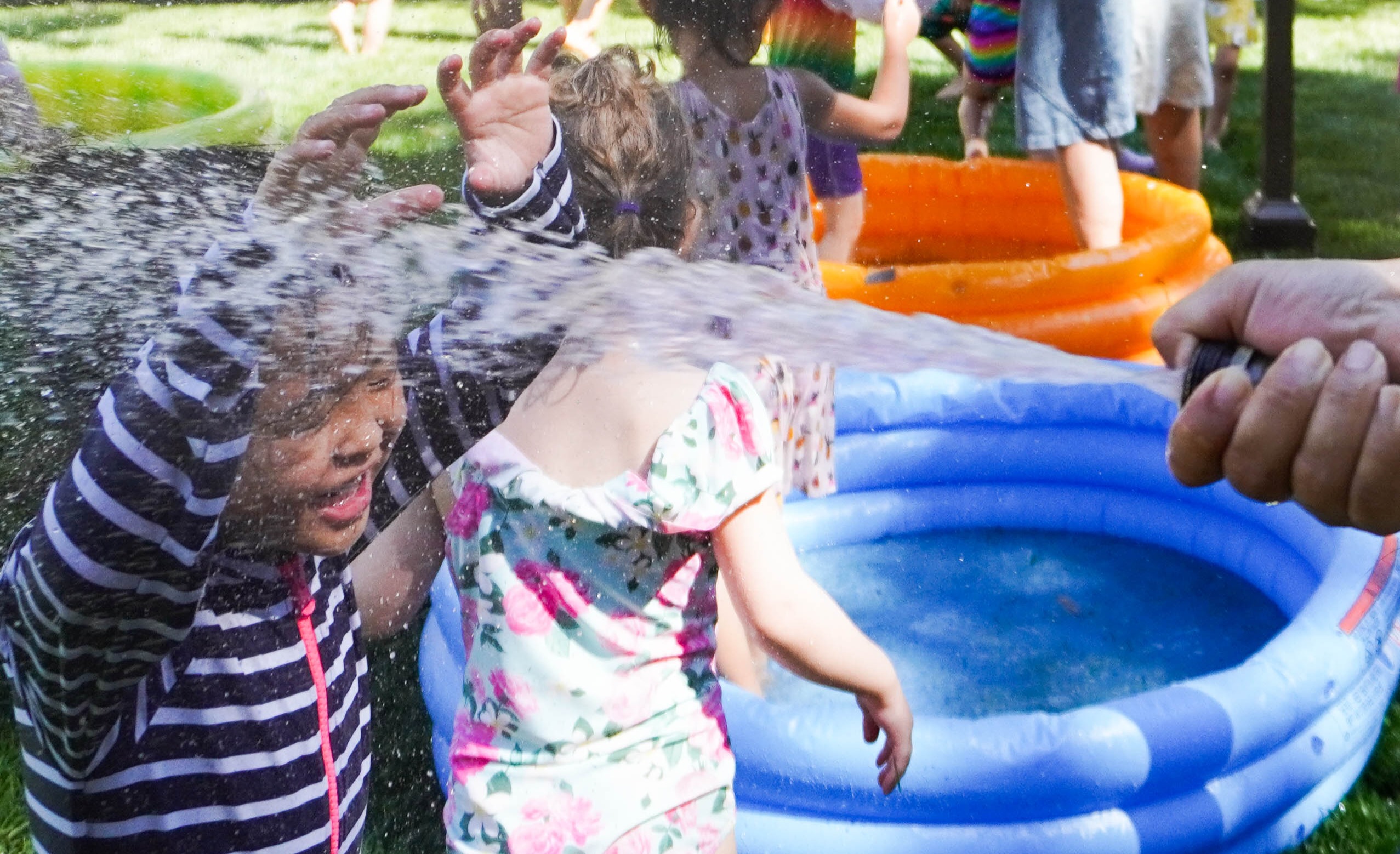 Early Yers students running under the hose during water play