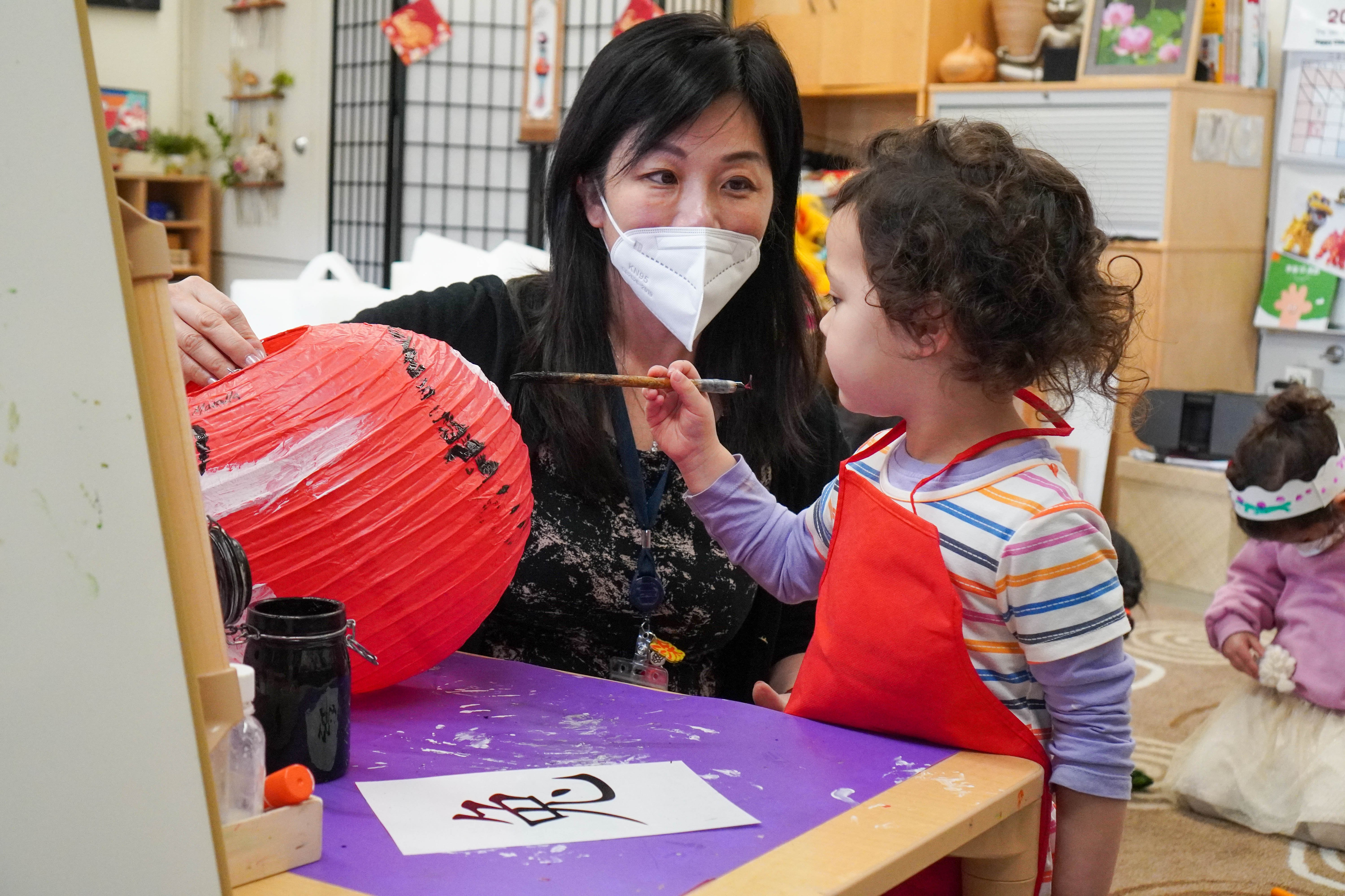 An Early Years student and her teacher paint a rabbit on a handmade lantern.