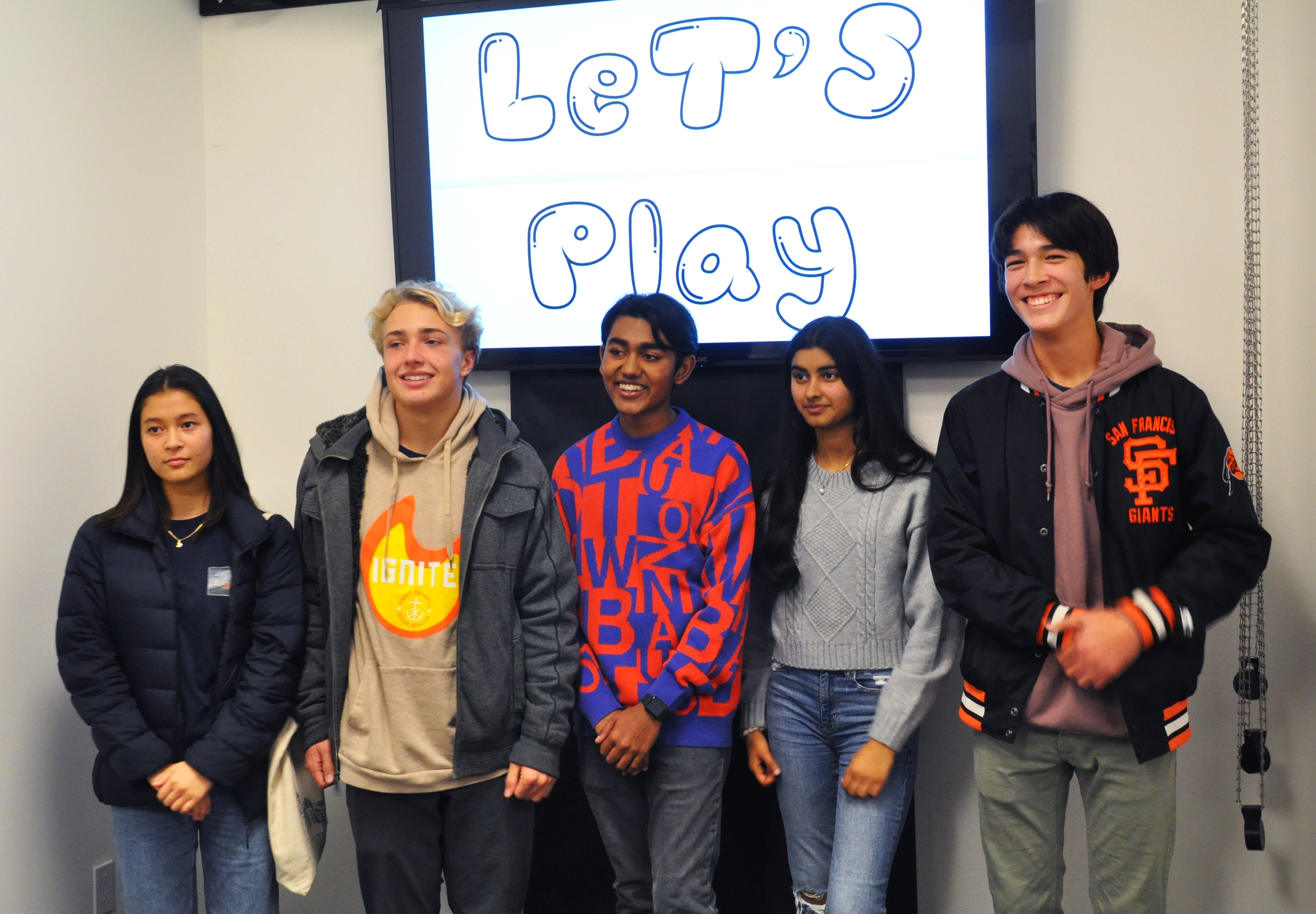 Current students and alumni pose for a photo under the Let's Play sign.