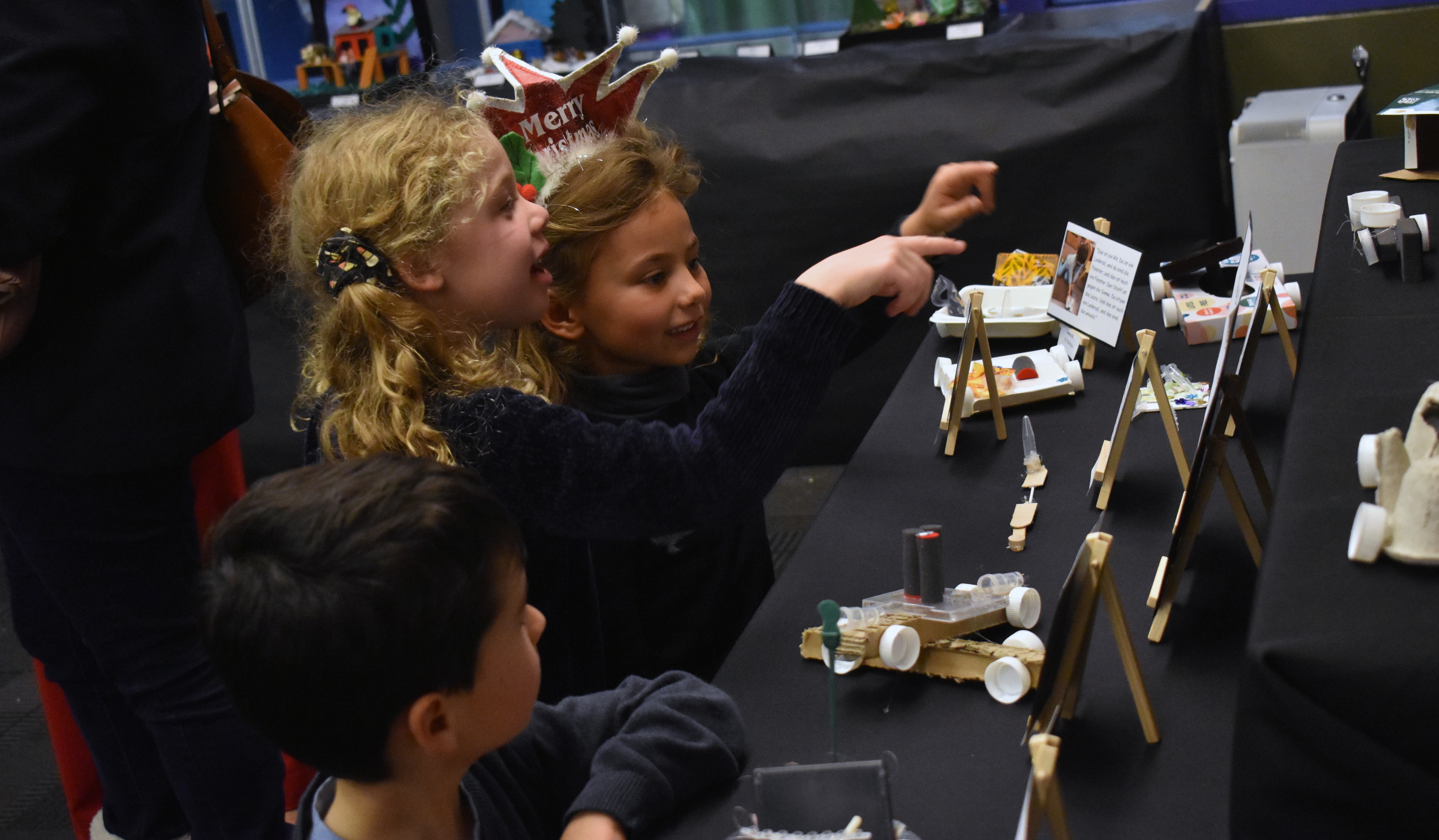 Three young students interacting with one of the displays.