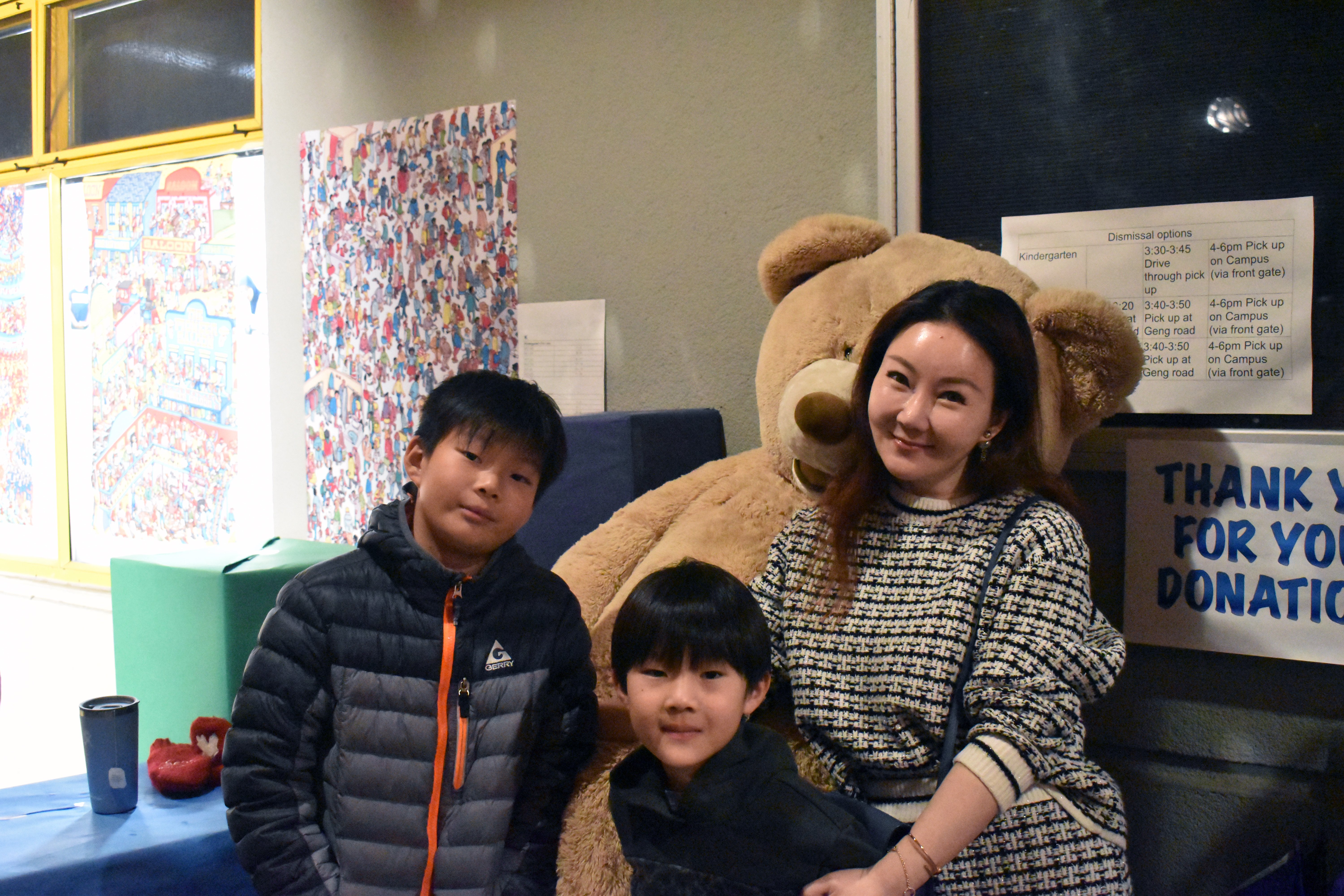 Mom and her two sons pose for a photo in front of the giant teddy bear outside of the Arts Night entrance.