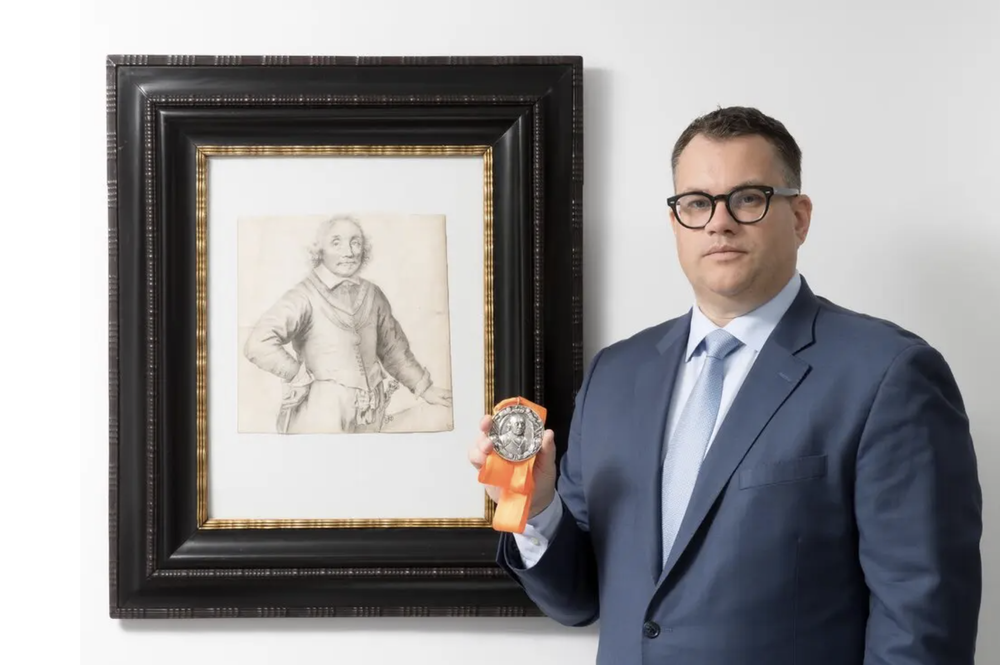 Mr. Bishop with the portrait of Tromp and a 17th-century silver commemorative medal depicting the admiral
