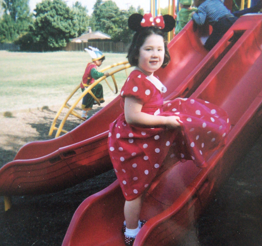 Isla Myles in her Disney Minnie Mouse dress standing on the slide at ISTP.