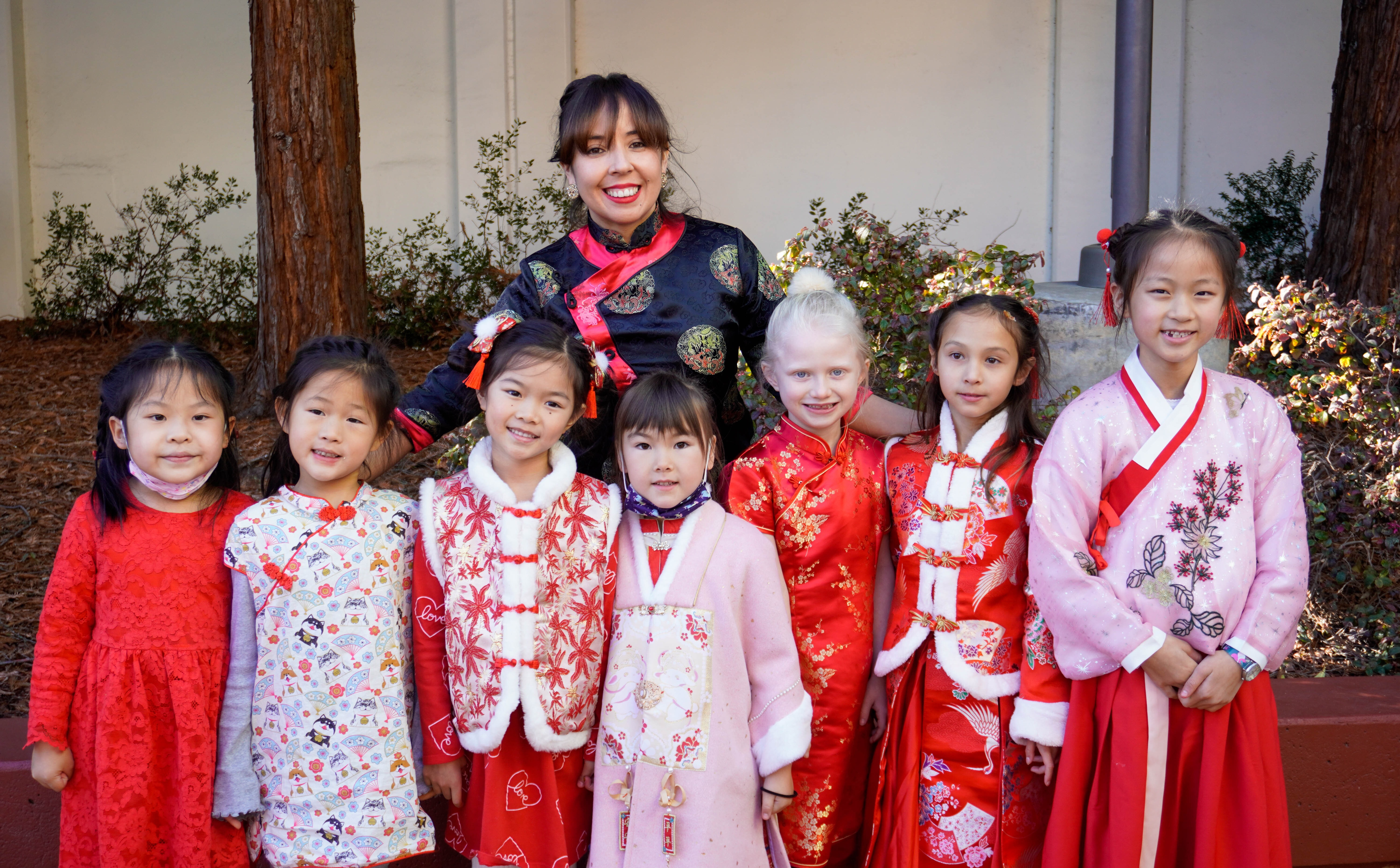 Seven elementary school girls wearing traditional red dresses for luck in the new year.