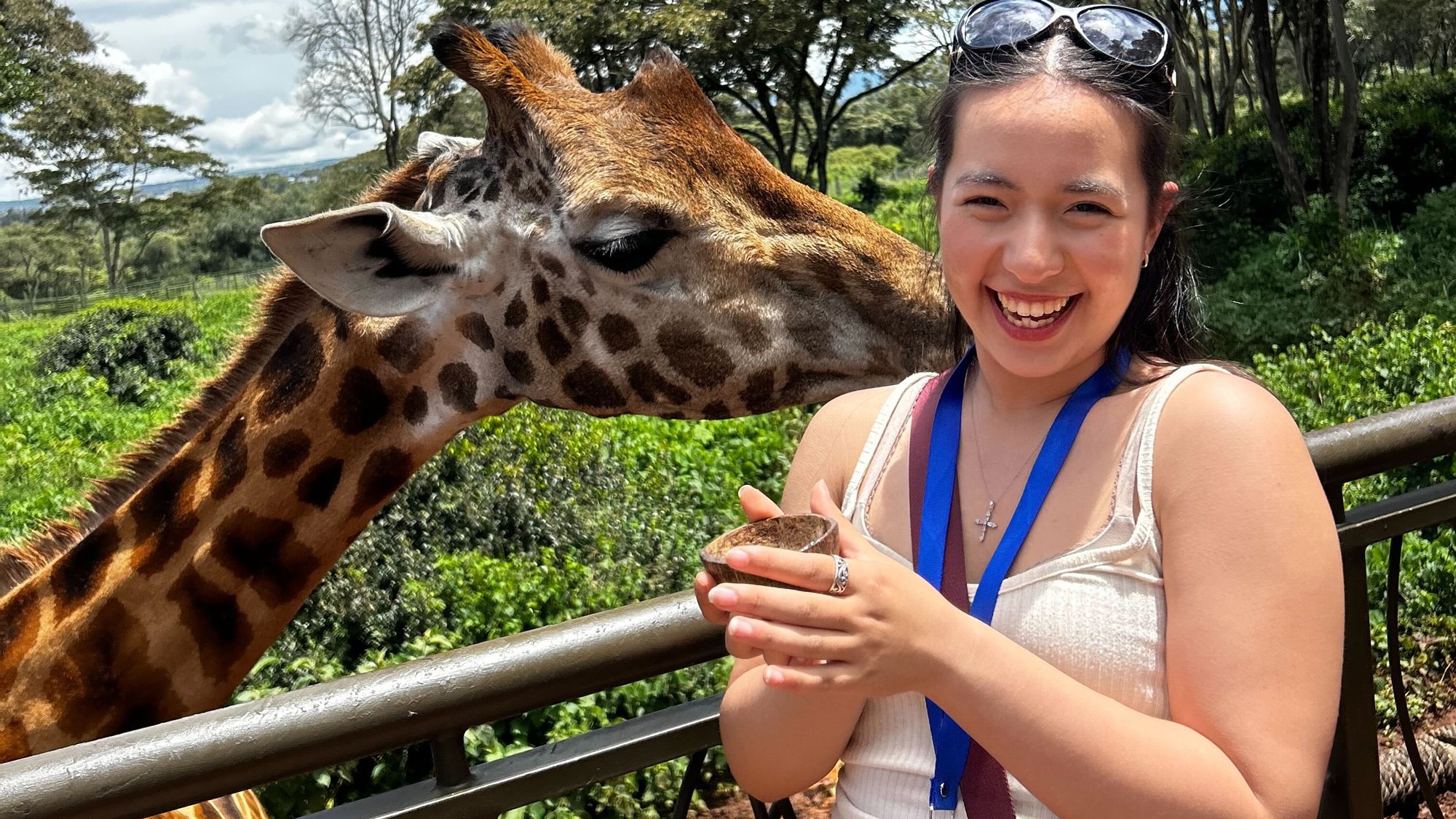 INTL student getting kissed on the neck by a giraffe.