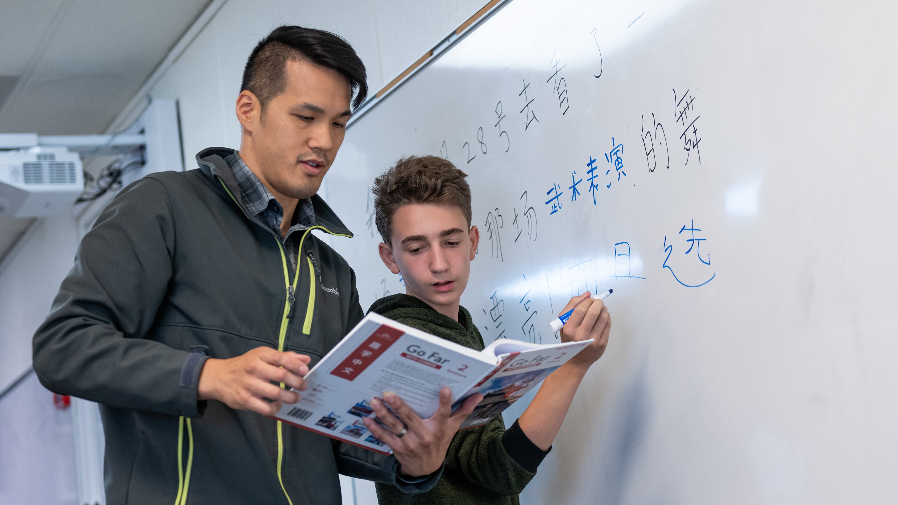Chinese Middle Schooler working at the white board with his teacher.
