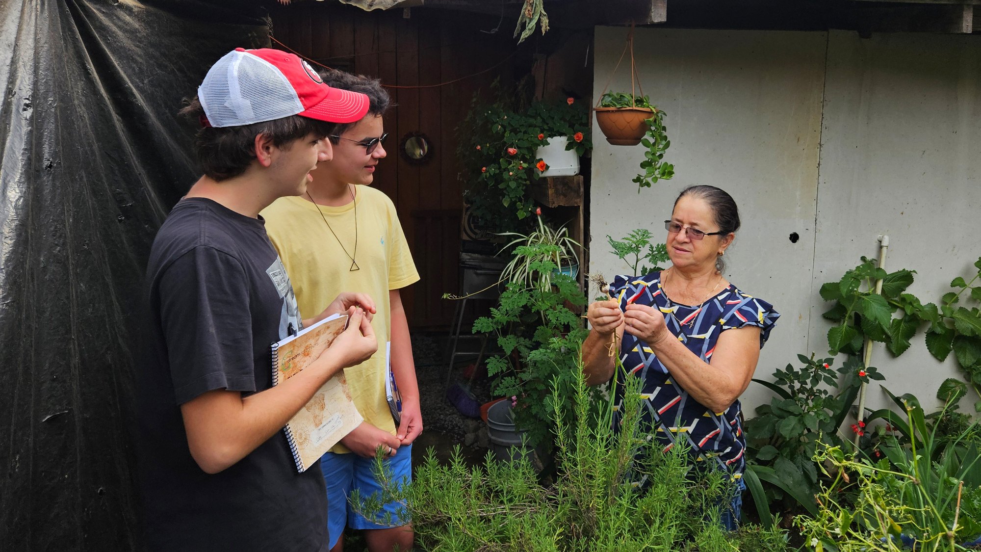 Two 10th Grade students speaking with a local in her garden.