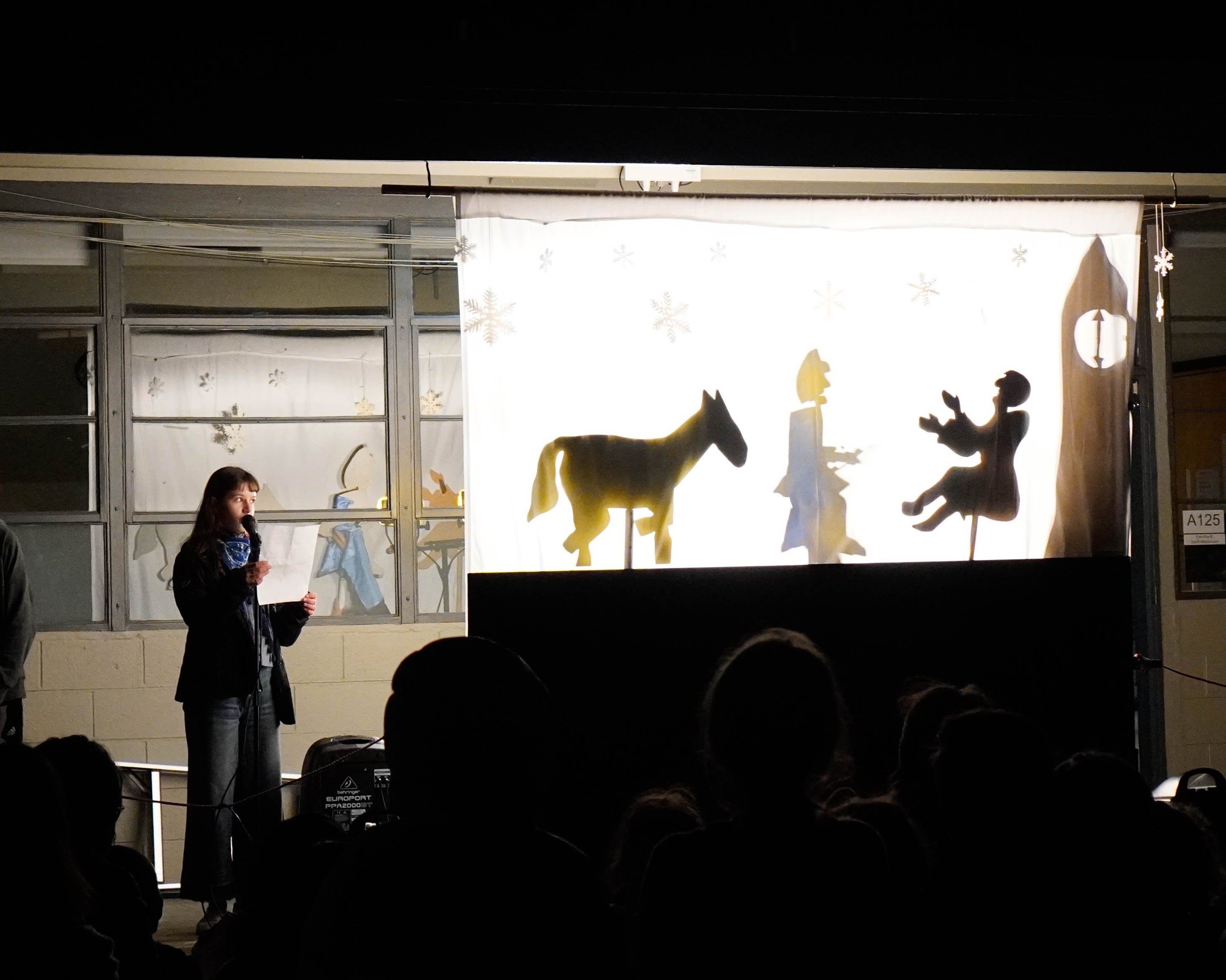 Upper School students and faculty putting on a shadow puppet play telling the story of St. Martin.