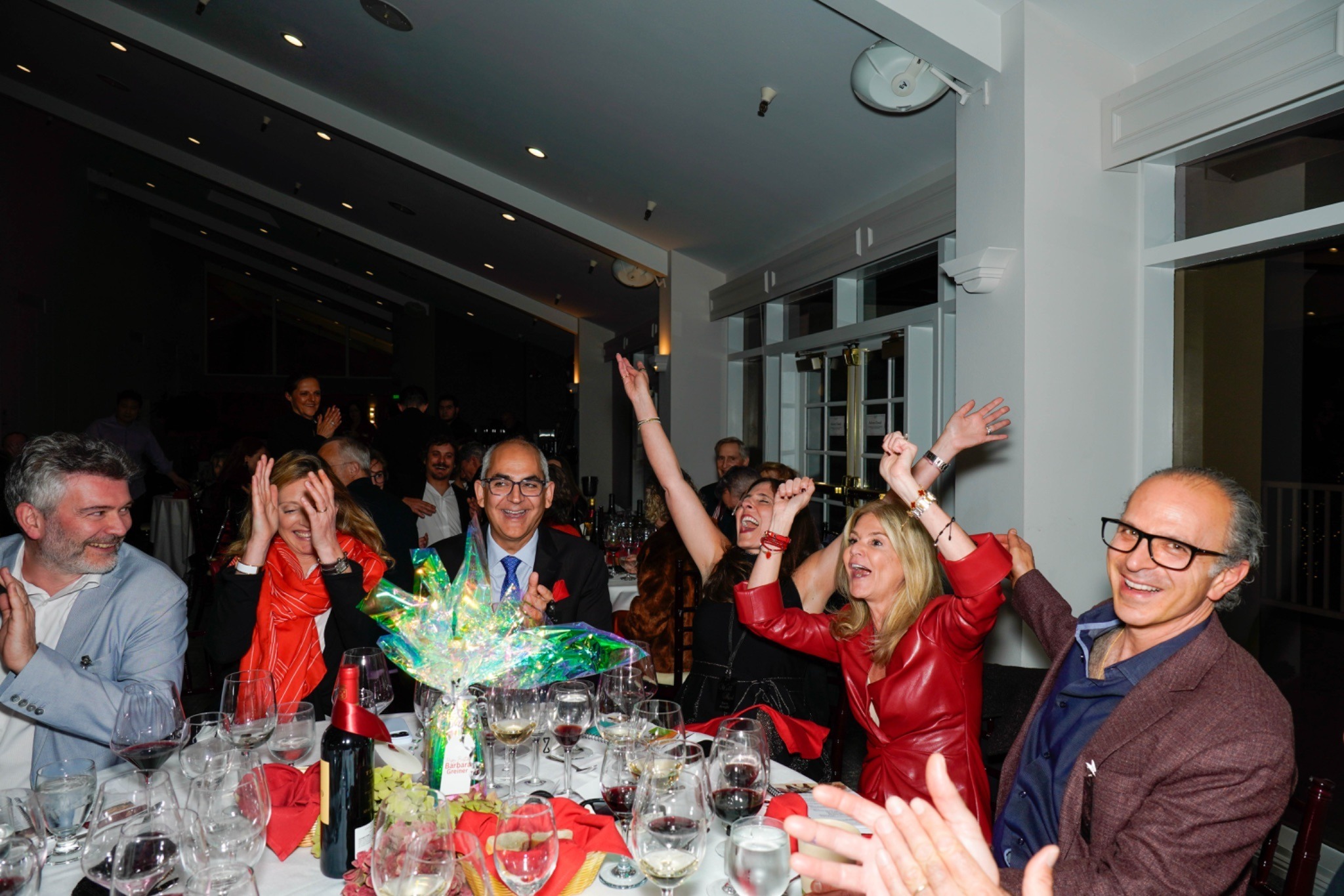 A table of six raucously celebrates a winning bid