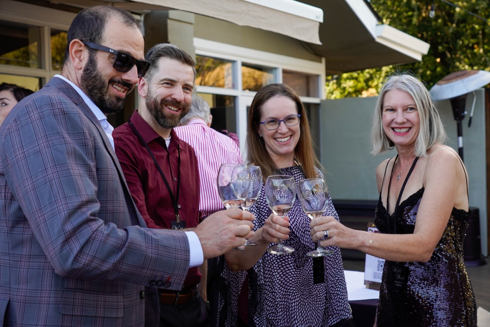 Two couples with white wine hold up their glasses or a photo