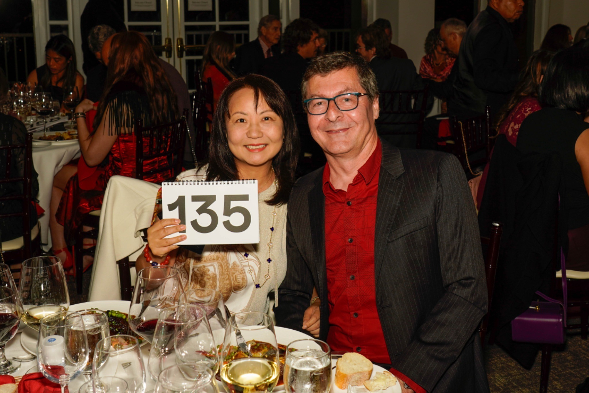 Two winning auction bidders holder up their auction paddle for the camera in celebration